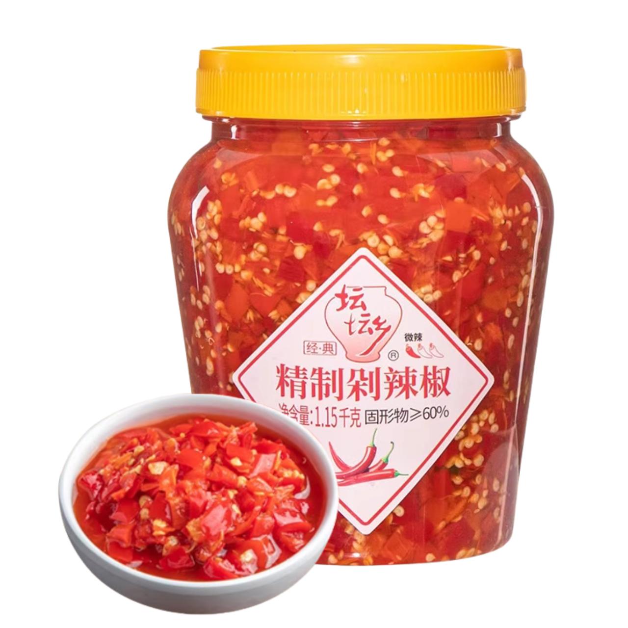 Jarra plástica grande de pimenta vermelha picada chinesa 精制剁辣椒, com sementes aparentes e tigela branca com porção de molho de pimenta à frente, embalagem 1,15kg