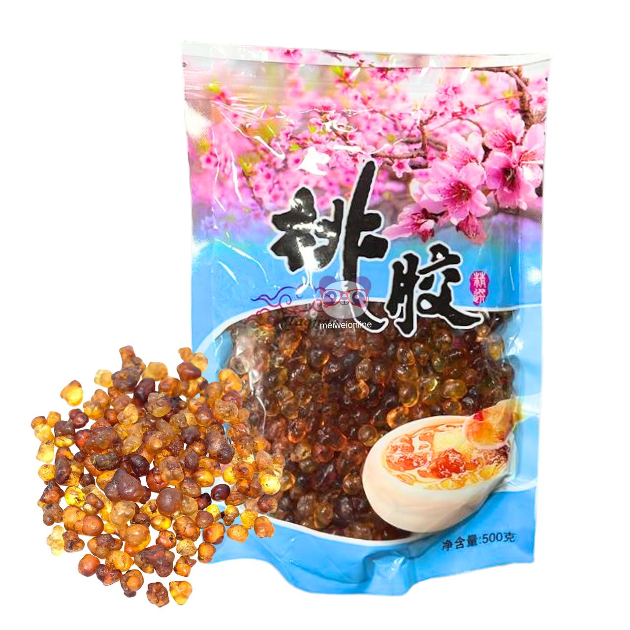 Embalagem azul de resina de pessegueiro 桃胶 Peach Gum 500g com flores de pessegueiro ao fundo, grãos de resina secos espalhados ao lado e tigela com sobremesa